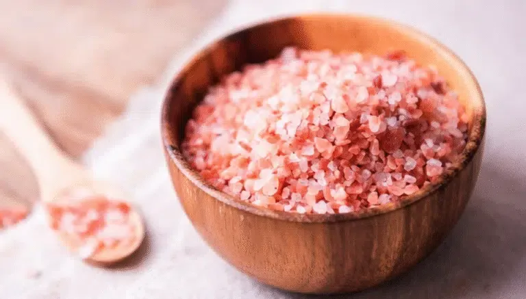 Close-up of Japanese pink salt crystals in a wooden bowl with a wooden spoon – natural unrefined mineral salt for cooking and health.