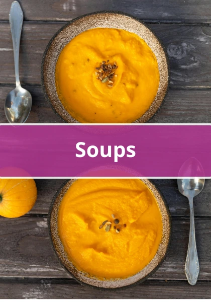 Two bowls of creamy orange pumpkin soup topped with seeds on a rustic wooden table with spoons.