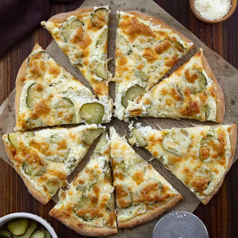 sliced pickle pizza topped with cheese and pickles, served with grated Parmesan and extra pickles on the side.