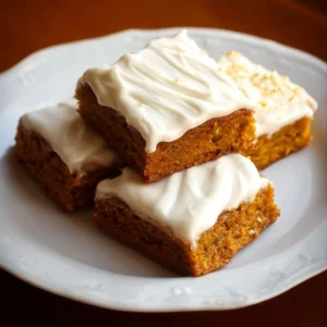 Delicious pumpkin bars with creamy cream cheese frosting on a rustic backdrop