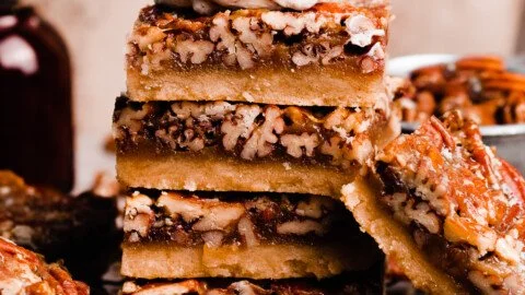 Salted maple pecan pie bars topped with crunchy pecans and a drizzle of maple syrup.