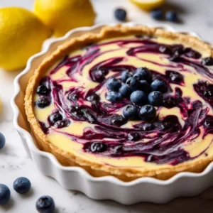 Creamy lemon tart with blueberry sauce on a white plate