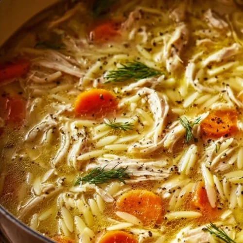 Bowl of Greek Lemon Chicken Soup with fresh herbs and lemon slices