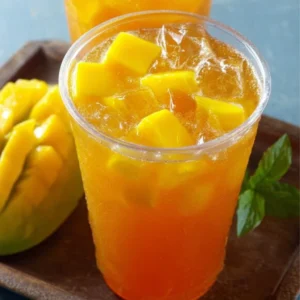 Refreshing glass of Mango Iced Tea garnished with fresh mango slices