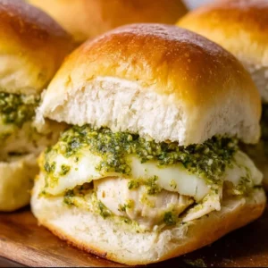 Cheesy garlic pesto chicken sliders served on a rustic wooden board