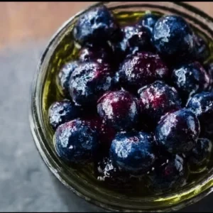 A jar of honey fermented blueberries showcasing vibrant color and texture.